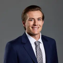 Professional headshot of Brett Garner wearing business attire, against a plain grey background.