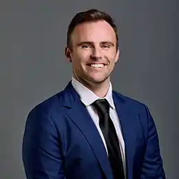 Professional headshot of Michael Steelman wearing business attire, against a plain grey background.