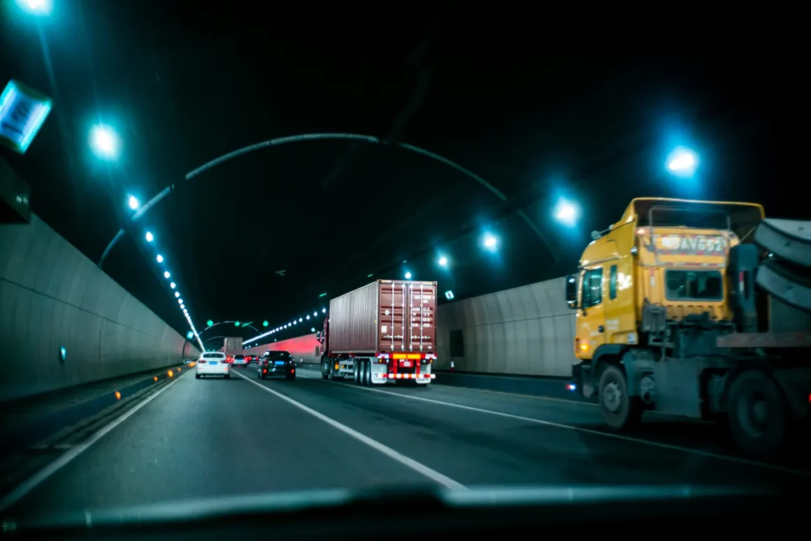 Semi-trucks driving through a tunnel with other passenger vehicles